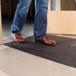 Man walking on New Pig grippy floor mat