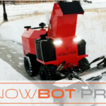 Red and black snow removal robot clearing snow from sidewalk