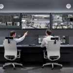 Two security professionals seated before a bank of monitors