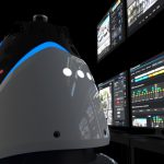 Human-height bullet-shaped robot next to operations center screens