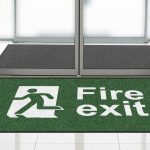 Green floor mat from First Mats with "Fire Exit" safety message