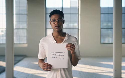 Young Black man holding a sign explaining the need for inclusive hygiene