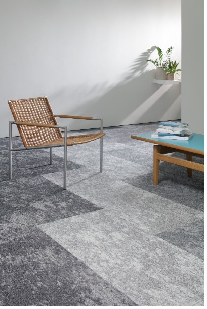 Milliken Northward Bound light and dark grey carpet tile with rattan chair and turquoise low table