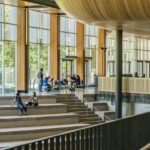 Architectural image of adult students sitting on steps and by tables