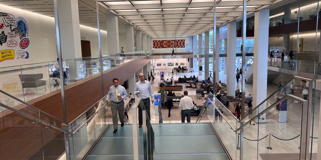 People on a glass-walled escalator inside a building