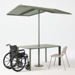 Table with shade, with wheelchair and regular chair next to it