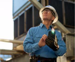 ABM Performance Solutions worker in hard hat with device